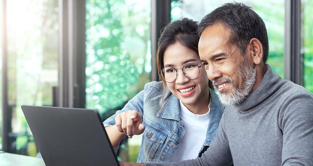 Couple looking and reading information on laptop