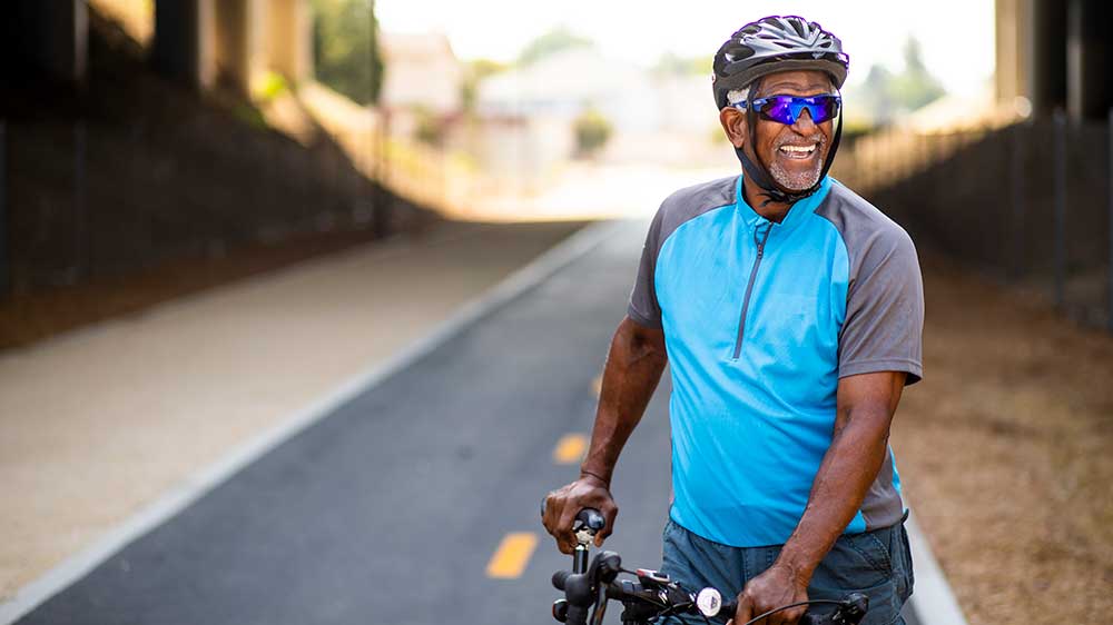 Man smiling on a bike | What causes colorectal cancer